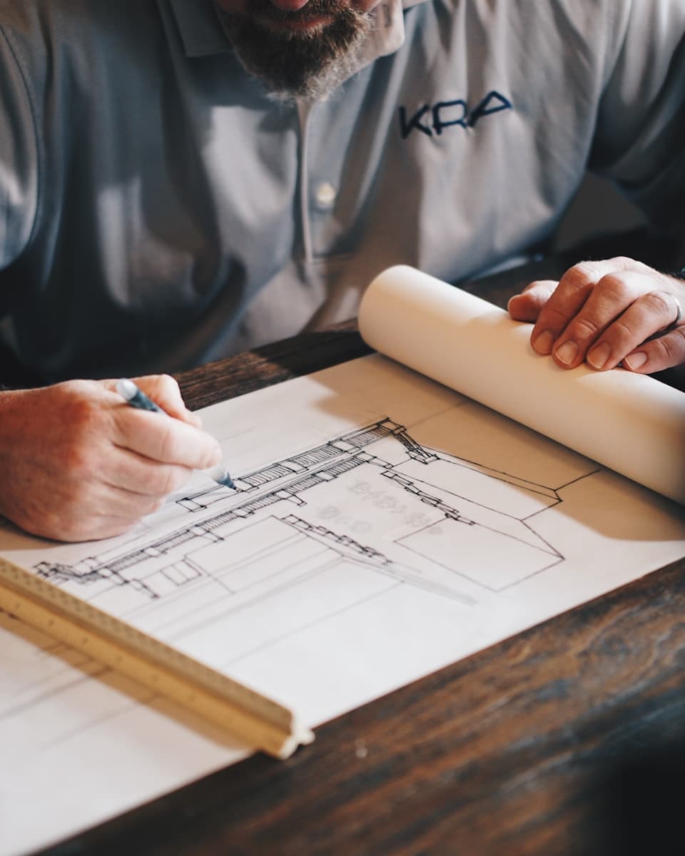 Hands drawing a plan on a drafting table