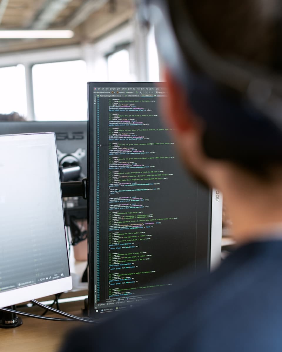 An engineer working at two screens in a small office